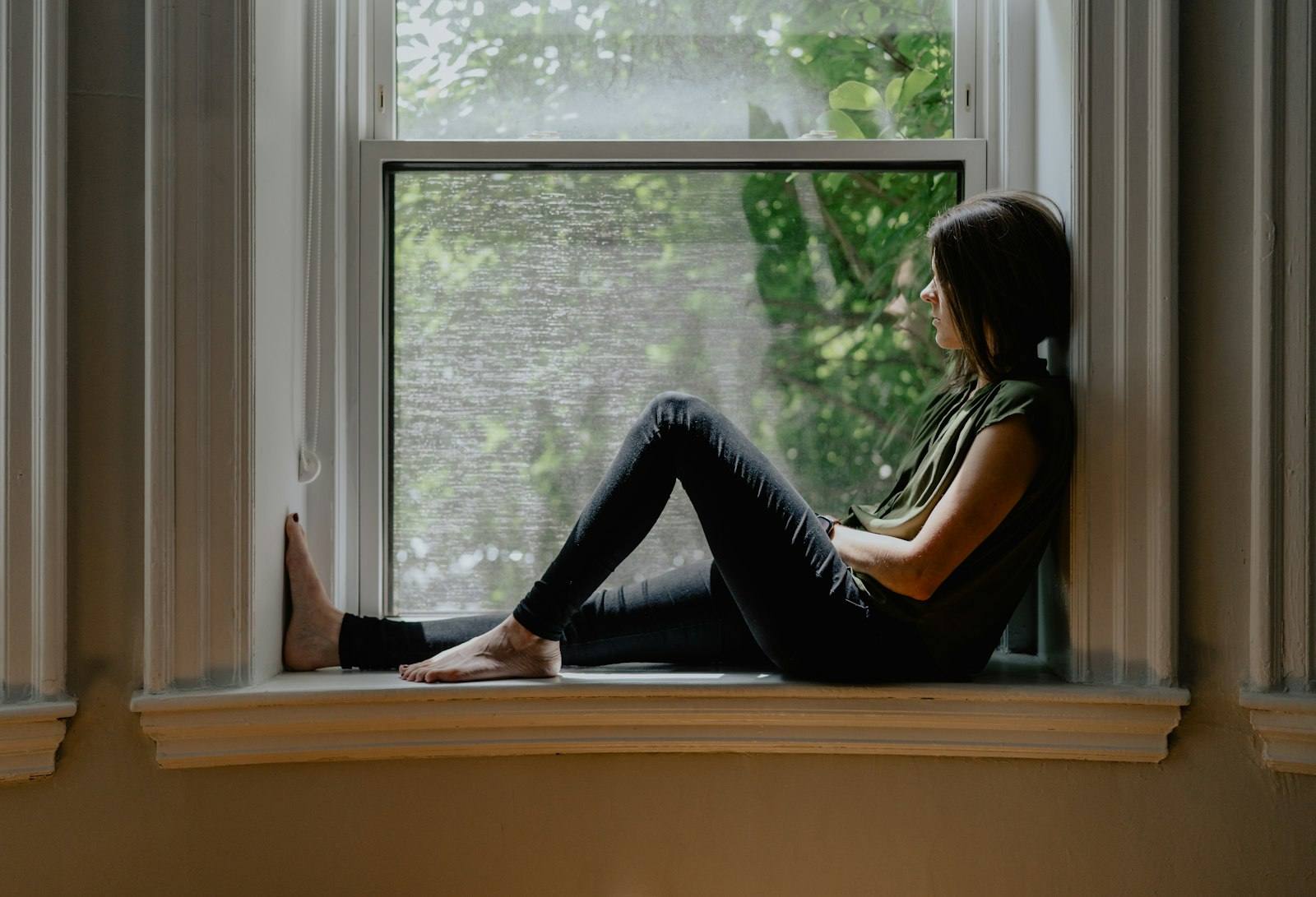 Woman sitting peacefully by a window with natural light